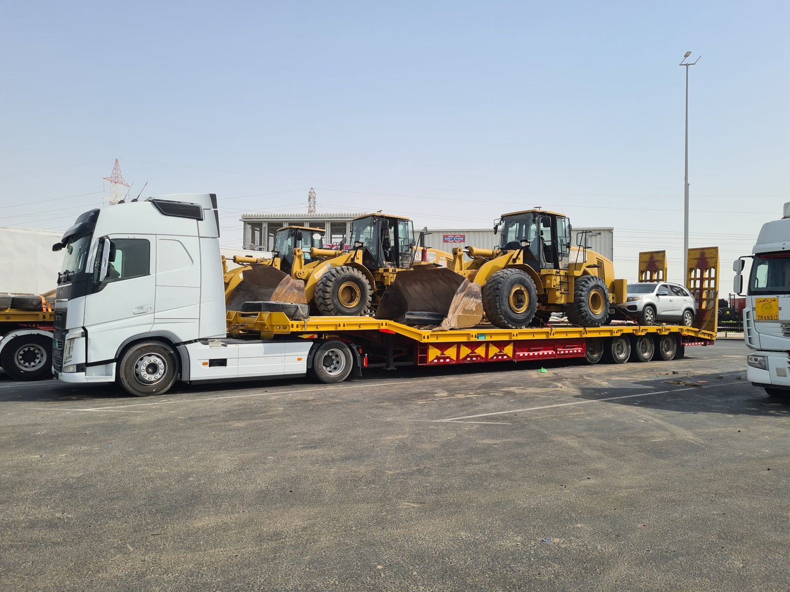 Two wheel loaders secured on a low-bed trailer